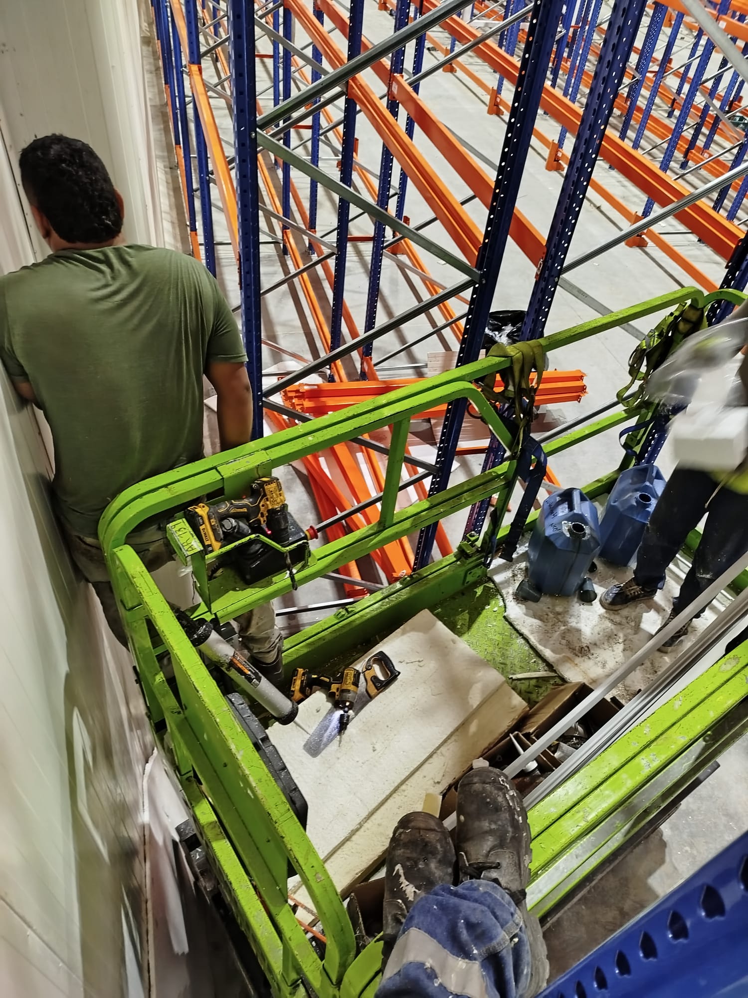 Operario trabajando desde una plataforma elevadora en una nave industrial