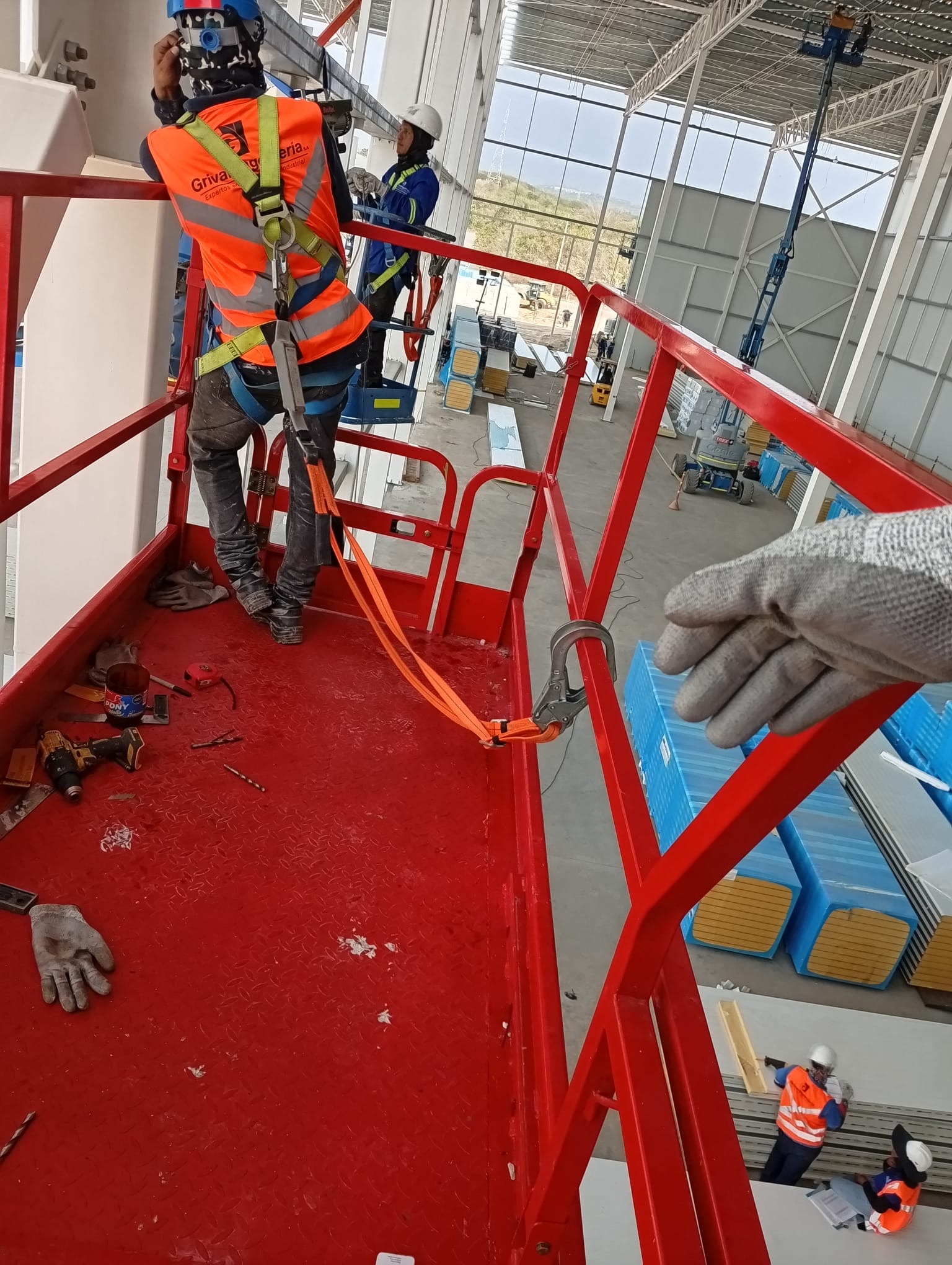 Equipo técnico trabajando desde una plataforma elevadora roja